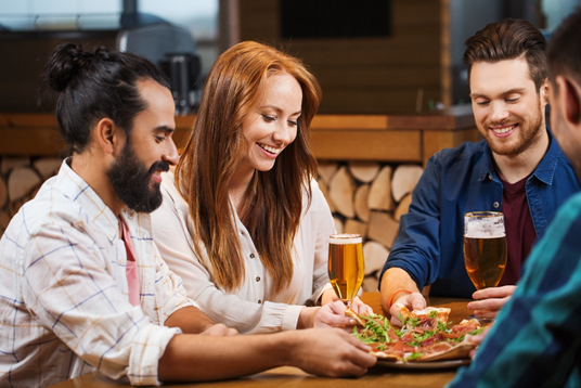 Friends sat having beer and pizza