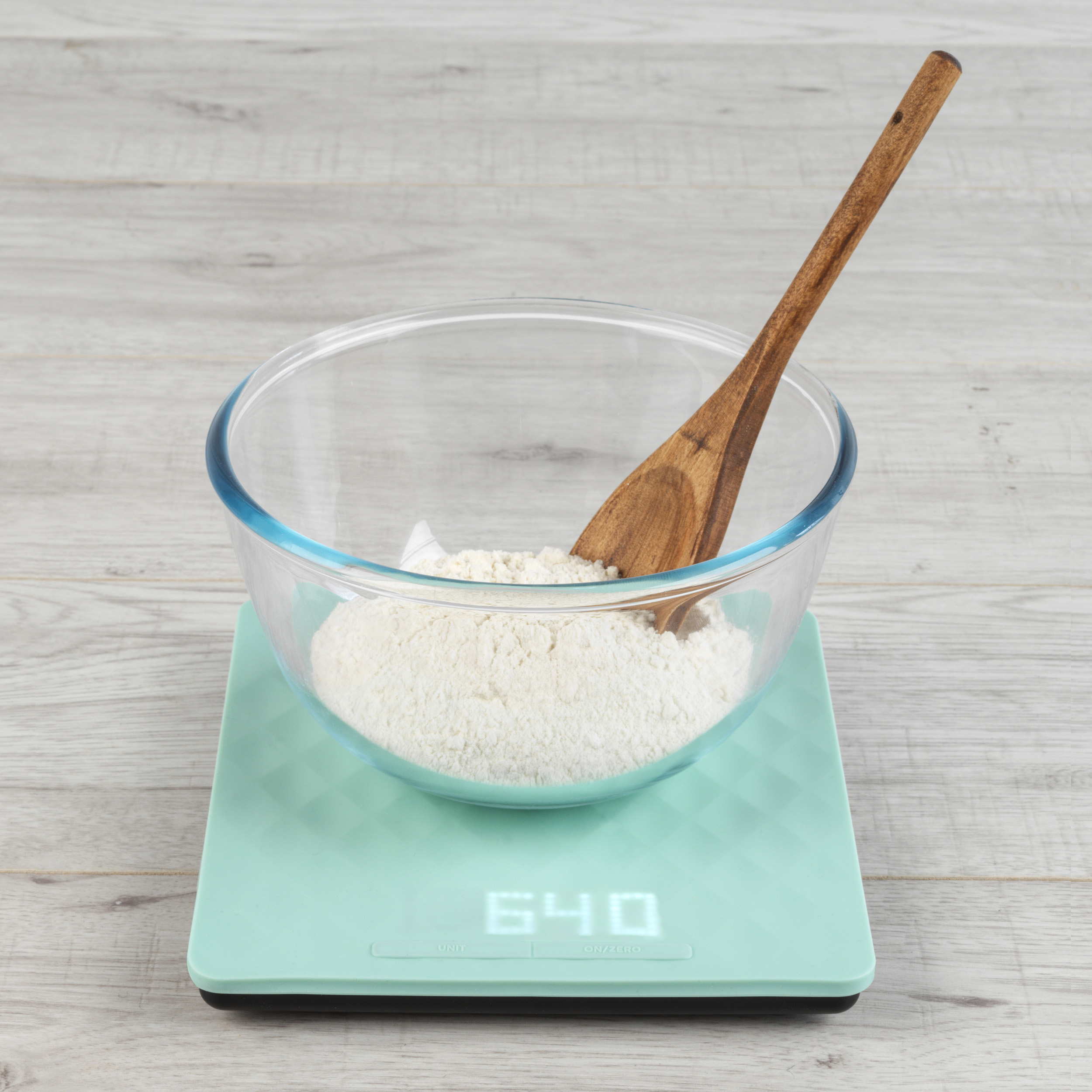 Flour in a bowl with a wooden spoon on Salter scales