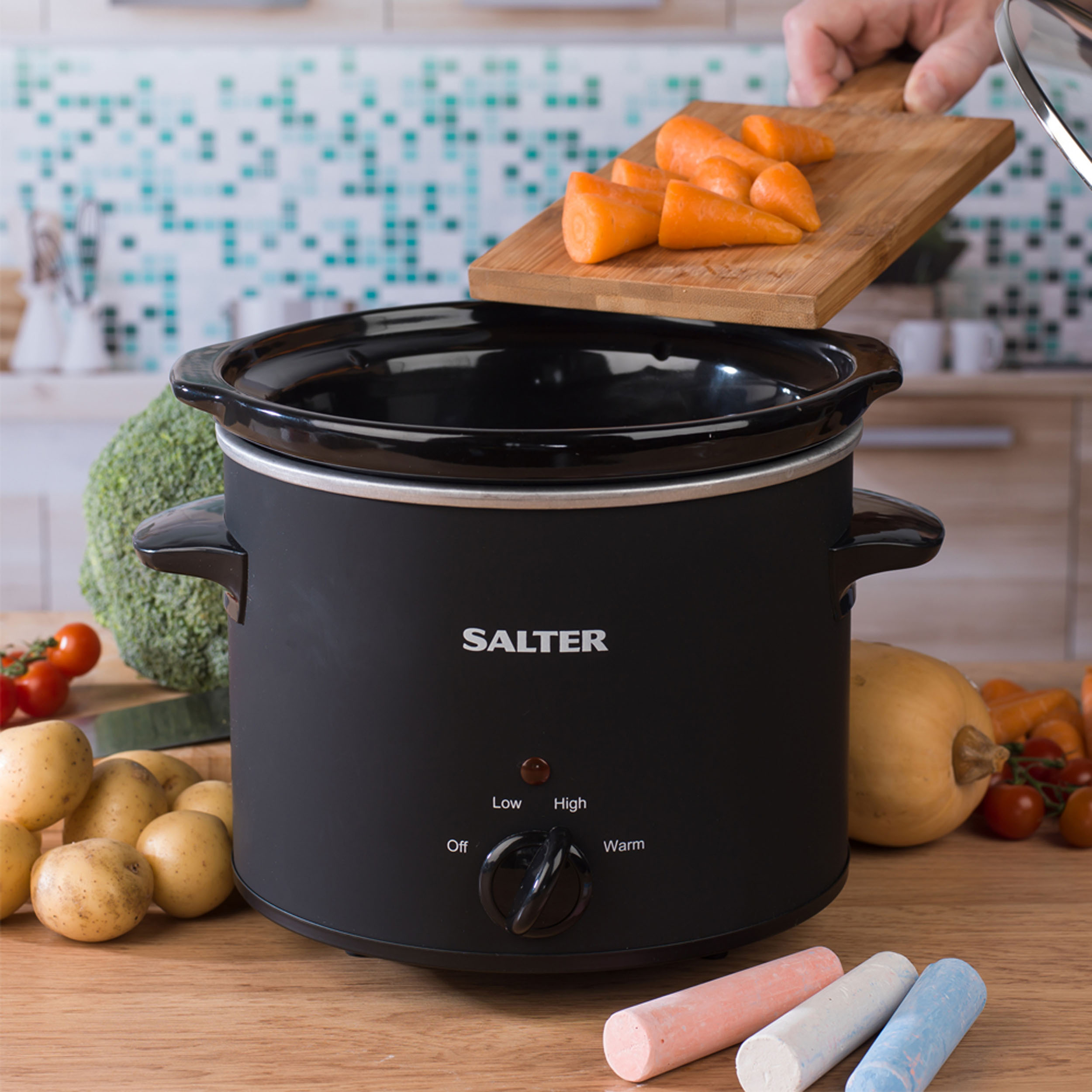 A Salter calkboard slow cooker with carrots being put into it