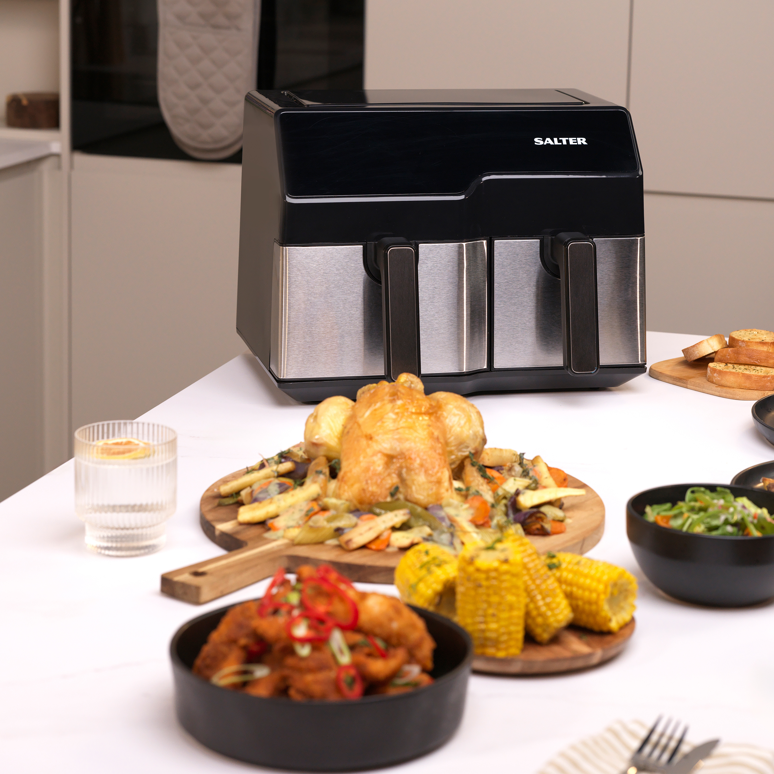 A Salter Digital Steam Air Fryer with chicken corn other foods in a kitchen