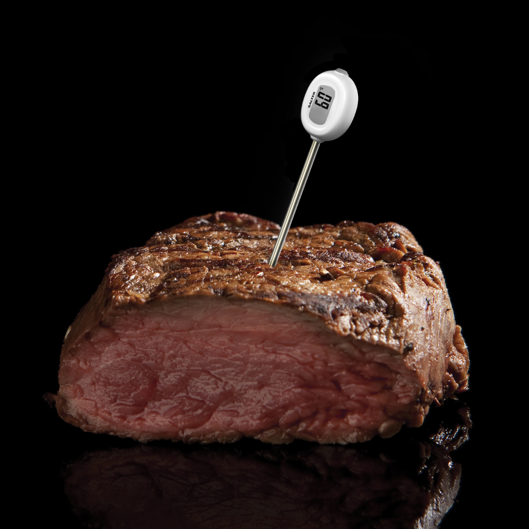 A large cooked stake with a probe thermometer stuck into it