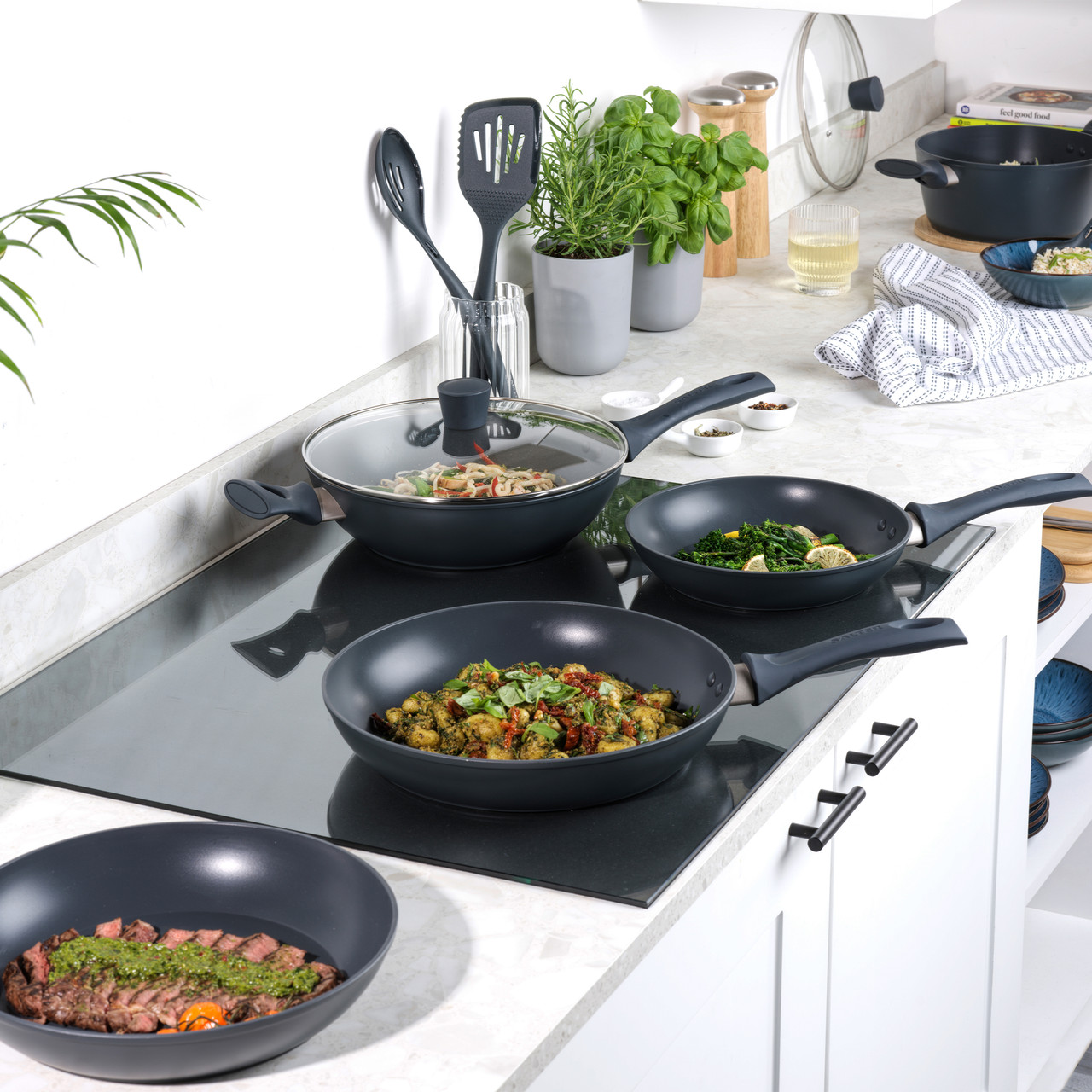 Various black Salter Kuro frying pans and Woks being used to cook food