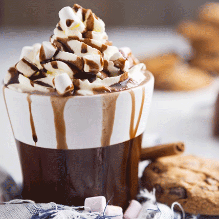 A cup of hot chocolate with cream and marshmallows on top and chocolate sauce dripping down the sides